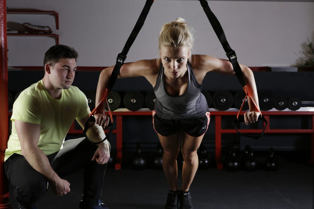A personal trainer helping a woman with an exercise 