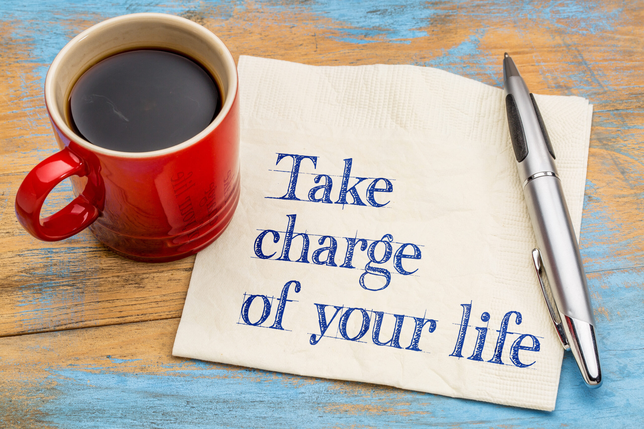 A coffee cup sitting next to a note that reads "Take charge of your life"