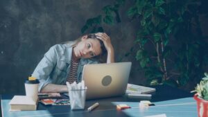 Exhausted woman at her laptop late at night, unable to switch off after work