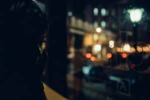 Woman looking out at city lights at night, nervous system still on high alert